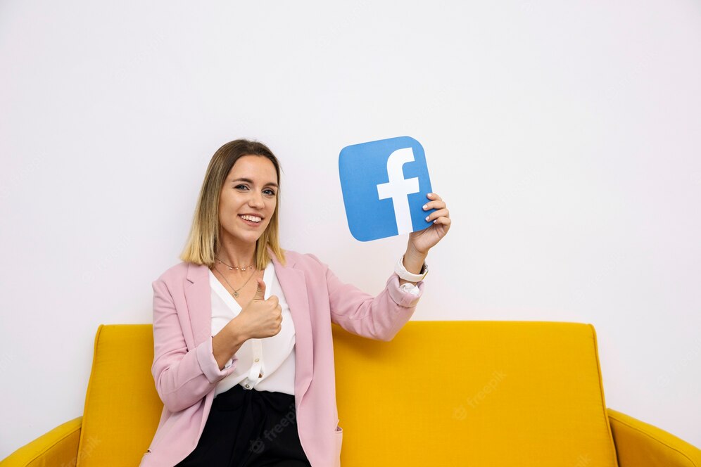 young-woman-sitting-yellow-sofa-holding-facebook-icon-showing-thumbup-sign_23-2147847508